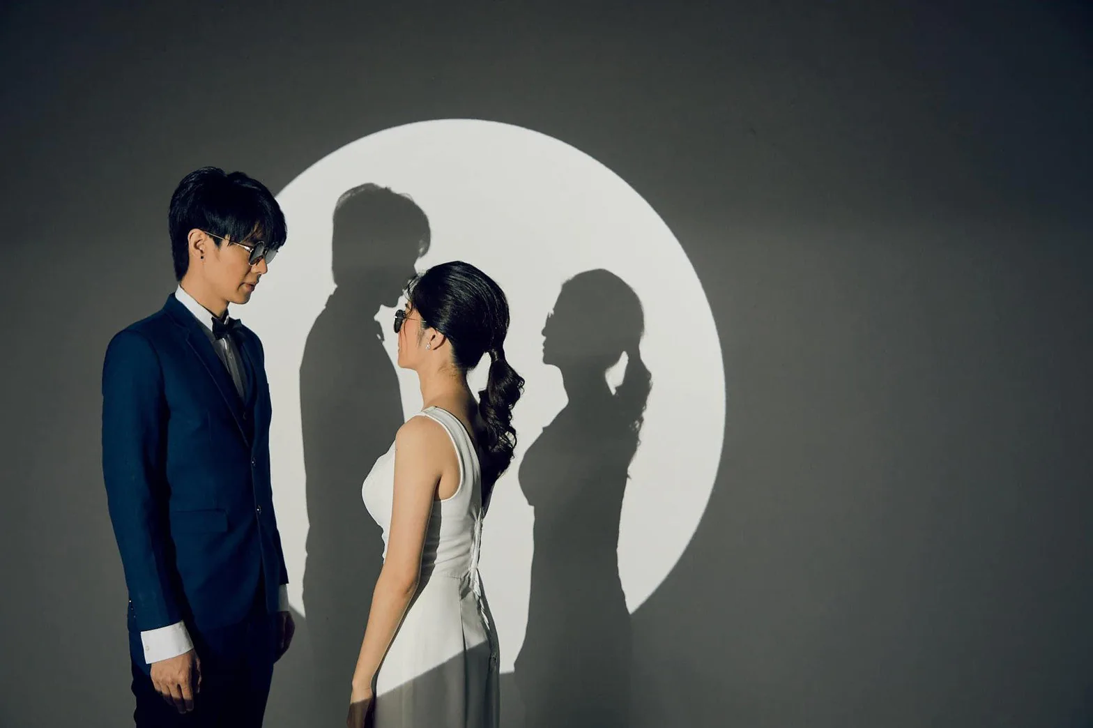 คู่รักในชุดราตรีและสูทกับแสงวงกลมในสตูดิโอ