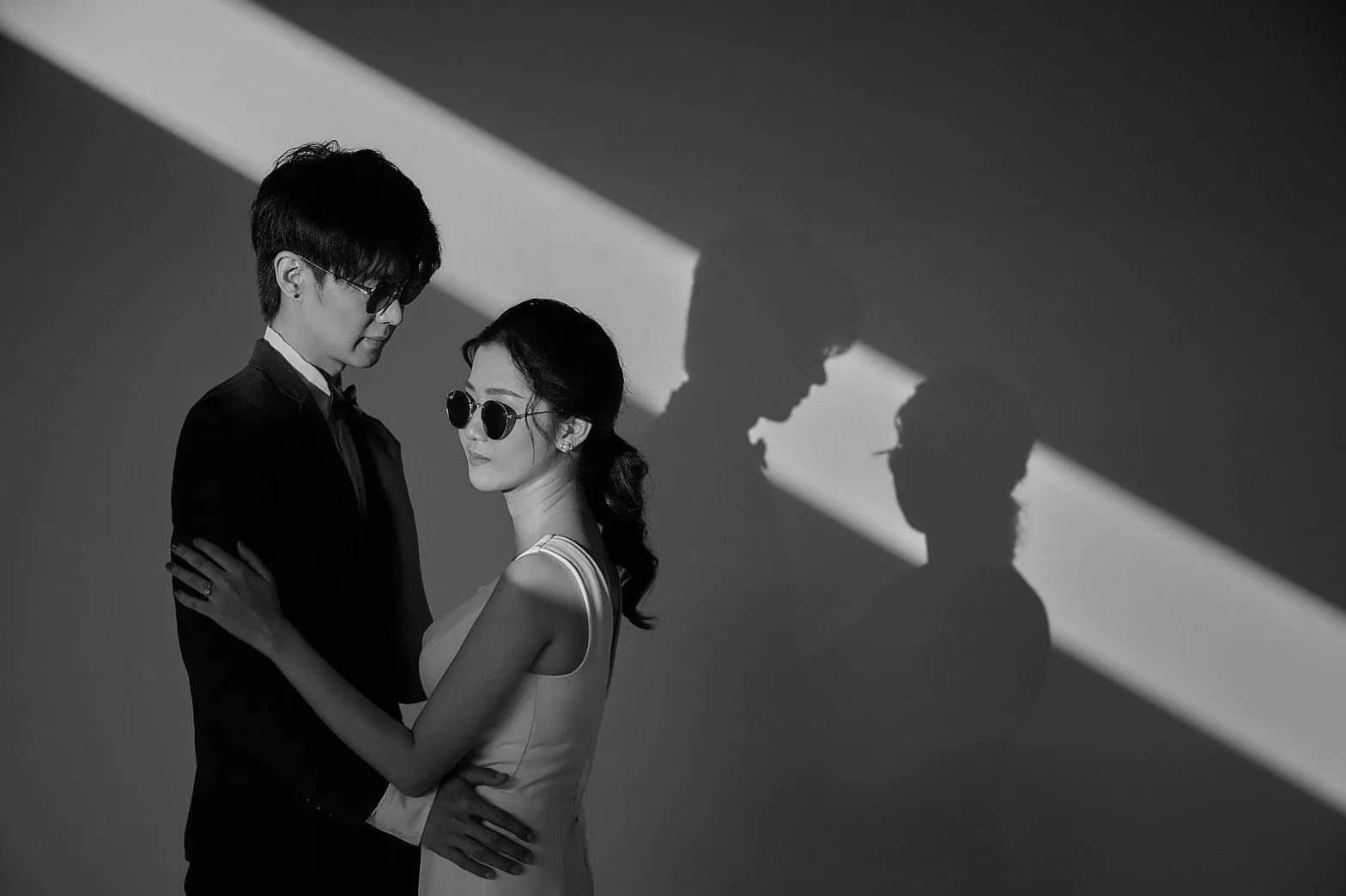 คู่บ่าวสาวในชุดราตรีและสูท ถ่ายภาพขาวดำกับแสงเงาที่สื่อรัก สตูดิโอ