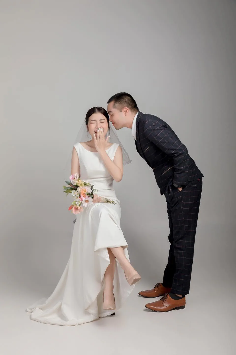 เจ้าบ่าวโน้มตัวคุยกับเจ้าสาวที่กำลังหัวเราะในสตูดิโอ