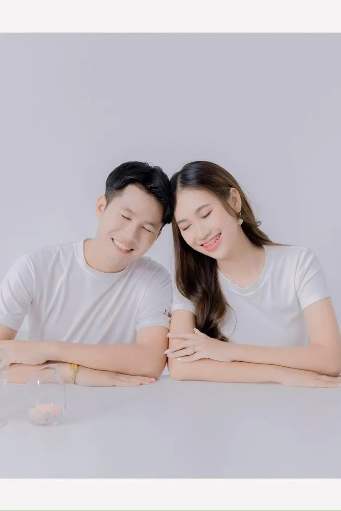 คู่รักสวมเสื้อยืดสีขาวนั่งพิงกันบนโต๊ะ